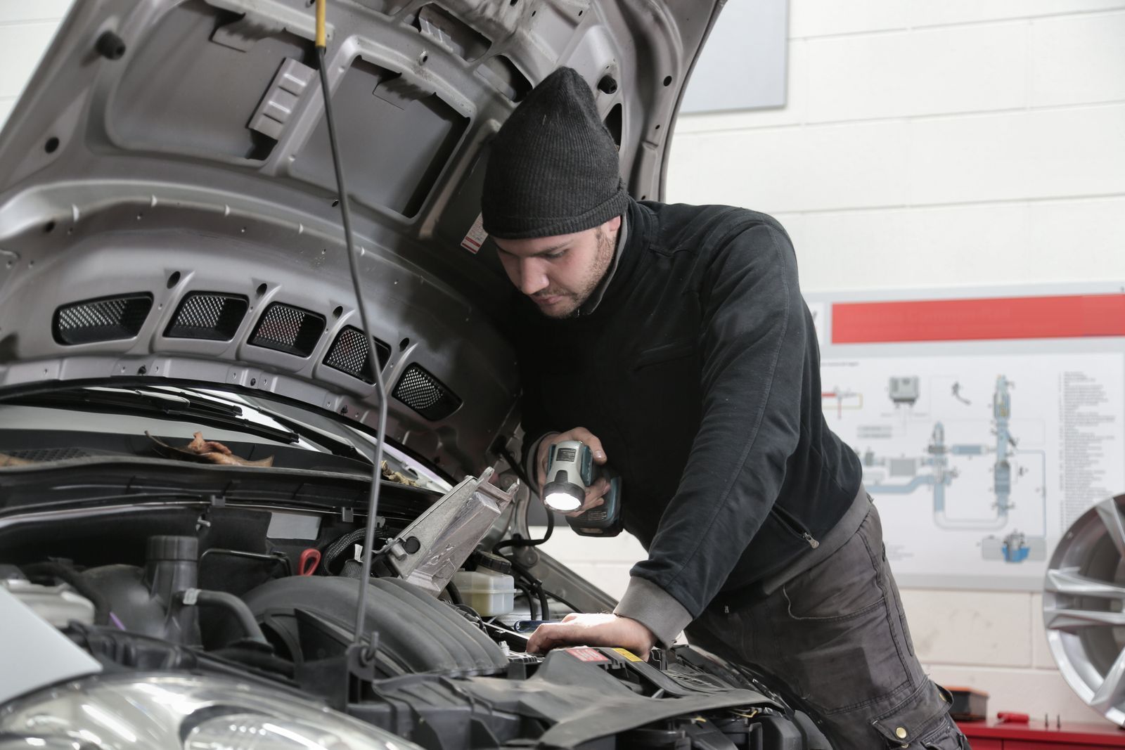 Mechanic shining a flashlight into an engine bay during an inspection